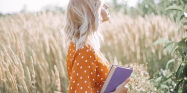 woman with a book in a field practicing self-care