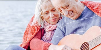 older couple embracing and playing a guitar