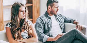 married man and woman sit on couch thinking about divorce