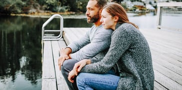 man and woman sitting next to each other on a dock or pier