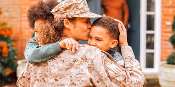 mom in military wear kisses two kids