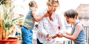 mother helping her two young children outside