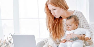 young mother holding child and looking at laptop
