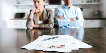 couple sitting at a table in front of paperwork with wedding rings on the top
