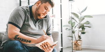 man writing in notebook in office