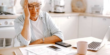 woman sitting at her kitchen table and worrying about her finances