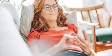 Woman lying on couch with a smartphone