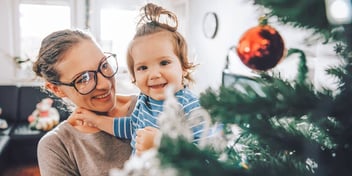 mom holding toddler by tree with red ball