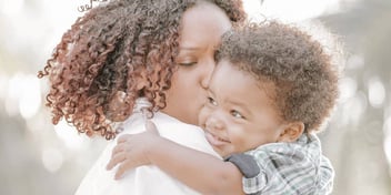 mom holding and kissing little boy