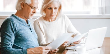 older couple sitting at computer looking at papers 