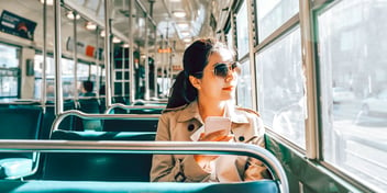 woman in bus seat looking out sunny window 