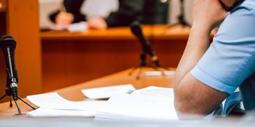 person sits at court mic desk with papers 