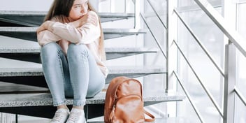 teenager with packed bag looks unhappy on stair step