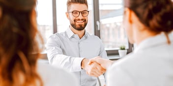 smiling man shakes hands with woman in professional setting