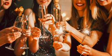smiling people clinking champagne glasses holding sparklers