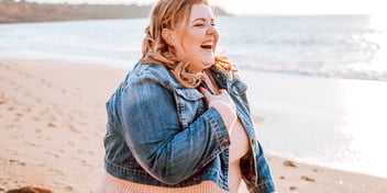 woman laughing on beach wearing jacket