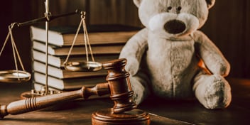 large teddy bear on desk next to judge gavel and stack of books