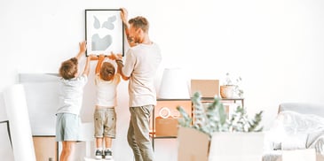 dad and two young boys hang new art on wall