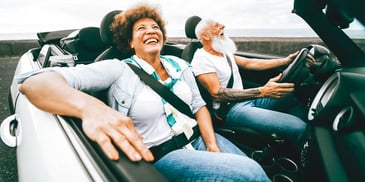 couple driving in car with top down and grinning