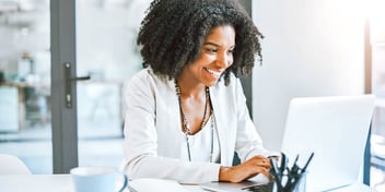 woman smiles as she types on computer