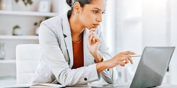 woman in blazer taps computer screen with stylus