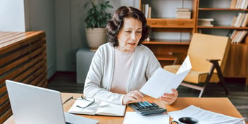 woman at desk with paperwork in hand