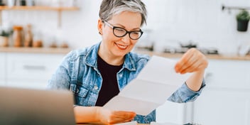 woman in glasses smiles at paper
