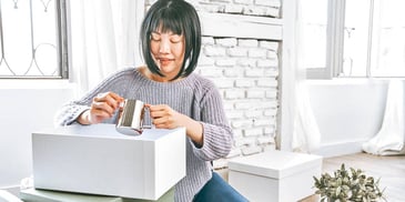 woman opens box to pull out silver item