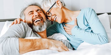 older couple laughing in bed