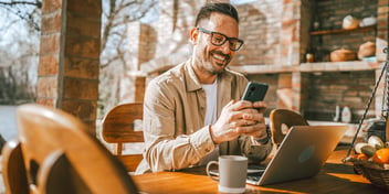 man in coffee shop smiling at phone