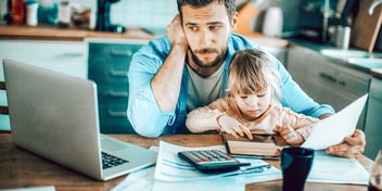 dad and child sit before calculator and laptop screen