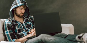 man in hoodie looking at laptop with dull expression