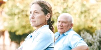 emotionally distant couple sitting far apart from each other in a park