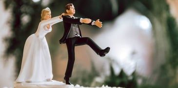 bride reaching for groom cake topper about to fall off cake