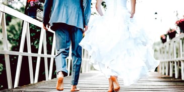 bridge and groom walking barefoot on a pier and holding hands