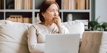 woman thinking with laptop sitting on a couch