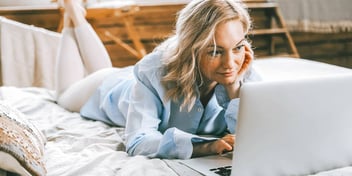 woman laying in bed and working on a laptop