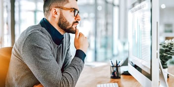 man looking over financial reports on a computer