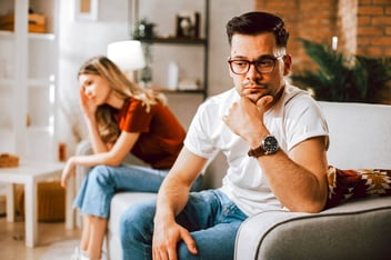 unhappy couple sitting far apart on a couch