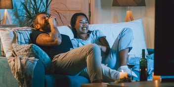 younger couple drinking wine and watching tv at home