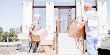 man and woman with moving boxes outside of a house