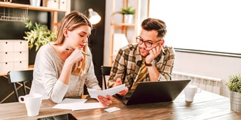 woman and man looking at paperwork and online forms together