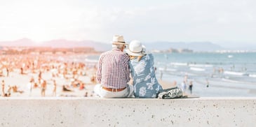 older couple sitting together on a beach overlook