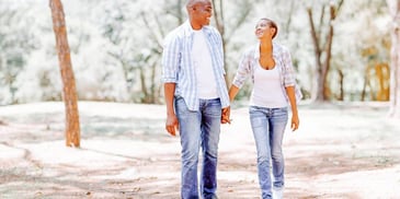 man and woman happy as they walk on a nature trail hand in hand