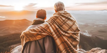 father and son embracing and sitting on a scenic mountain overlook