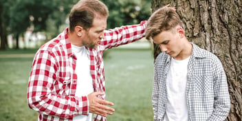 father talking to his cowering, ashamed teenage son