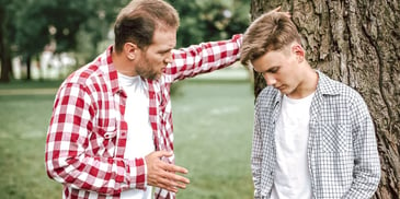 father talking to his cowering, ashamed teenage son