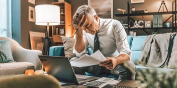 man holding his head in frustration as he looks over his bills