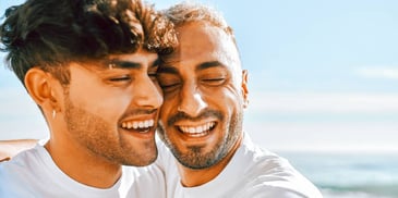 close-up of a male couple embracing on a beach