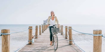 happy woman riding a bike on a pier by the ocean
